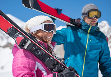 happy couple holding ski equipment